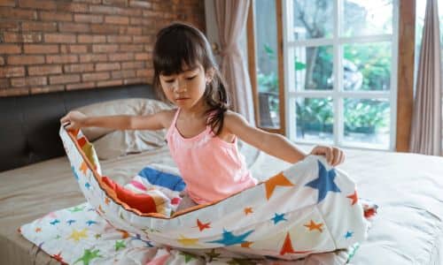 rutinas positivas para los niños- Una niña haciendo la cama.